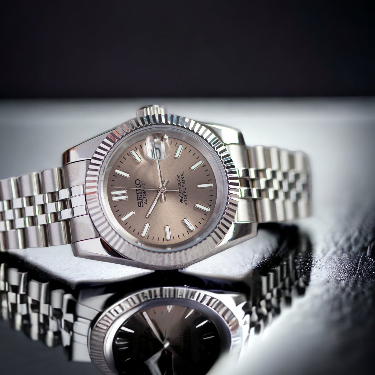 angled close-up of champagne sunburst dial Seiko mod watch with date window and fluted bezel