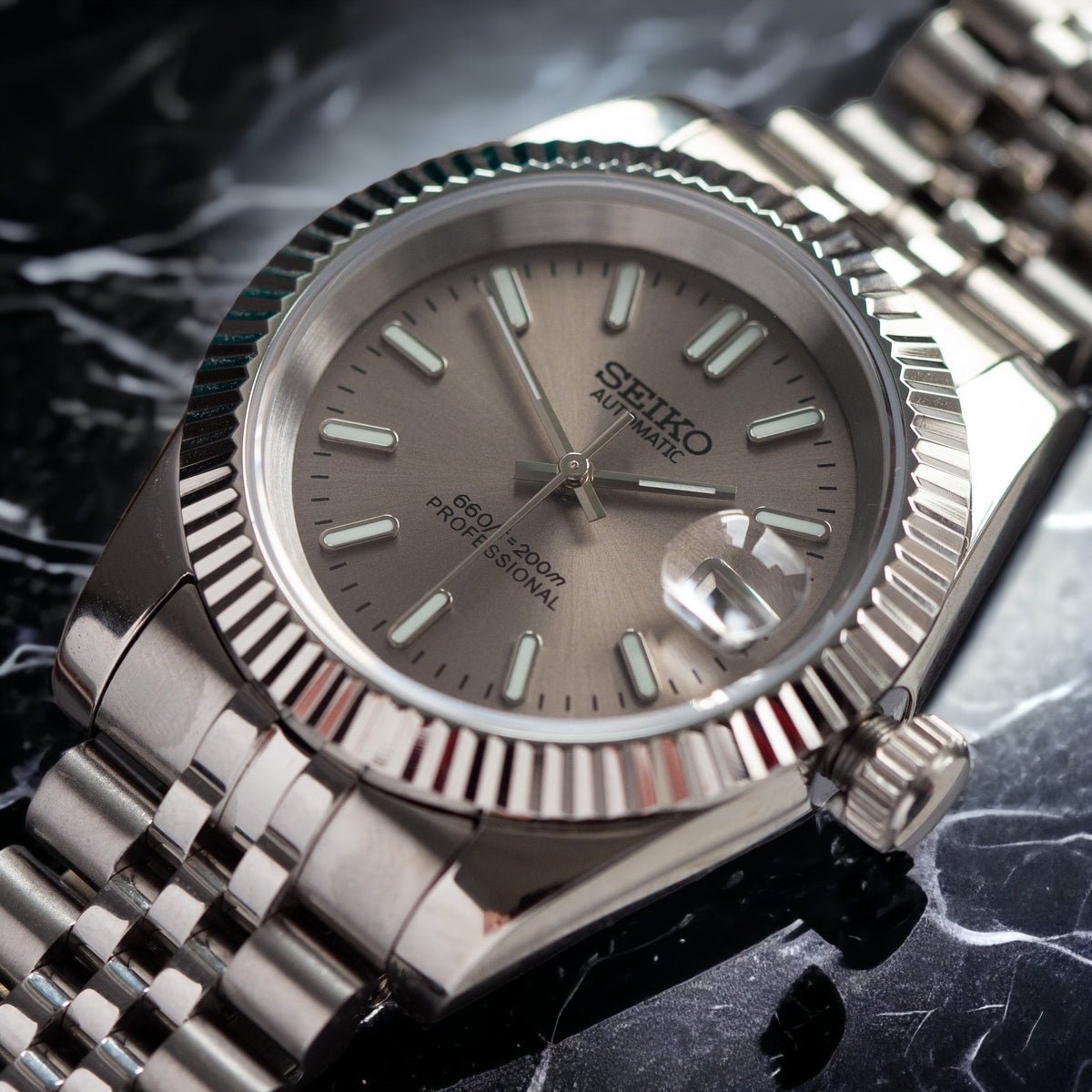 angled close-up of champagne sunburst dial Seiko mod watch with date window and fluted bezel