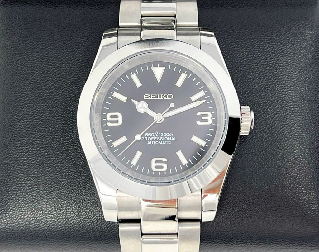 angled close-up of black 3-6-9 dial Seiko NH35 mod watch showing hands and indices