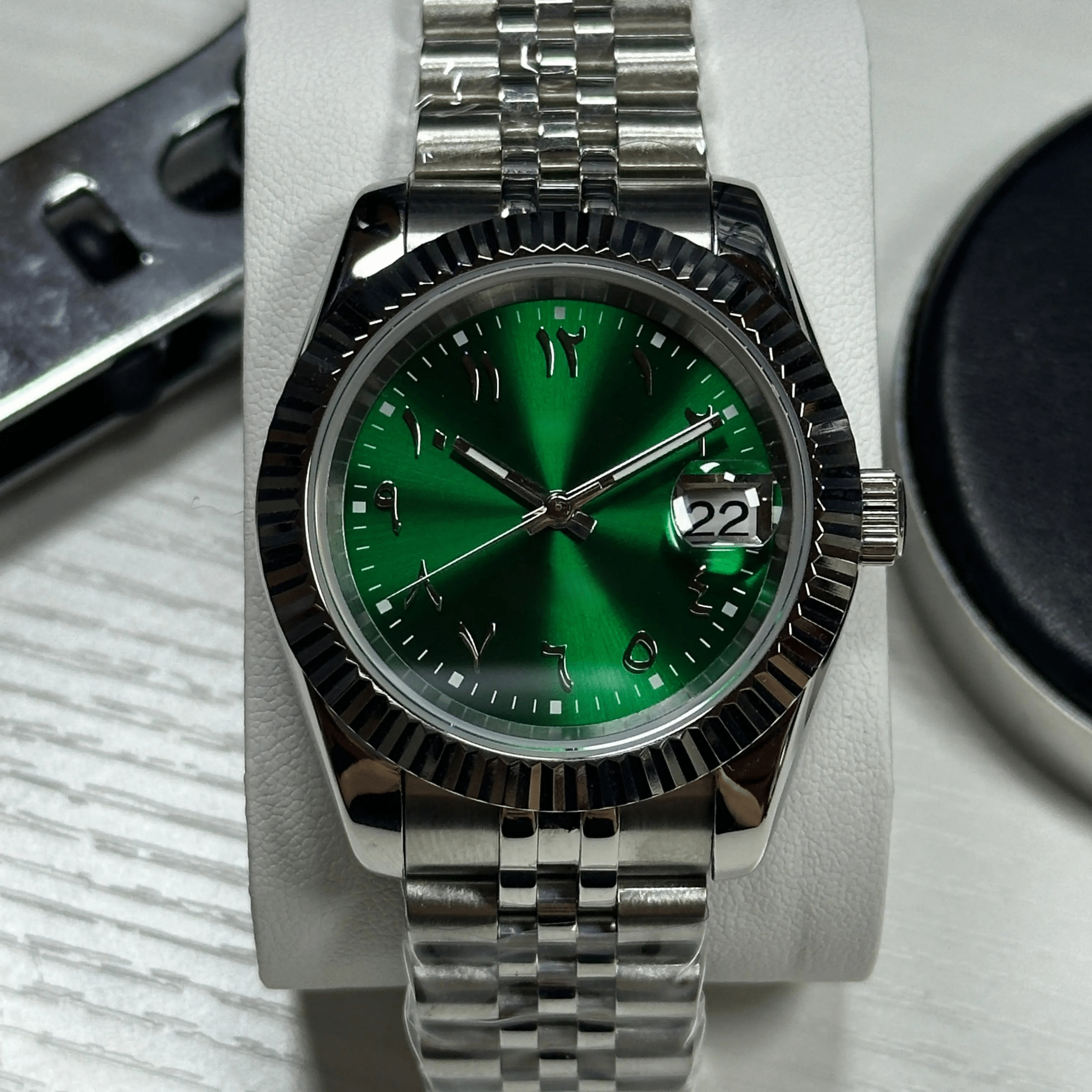 stainless steel Seiko NH35 mod with green Arabic dial, close-up on wrist