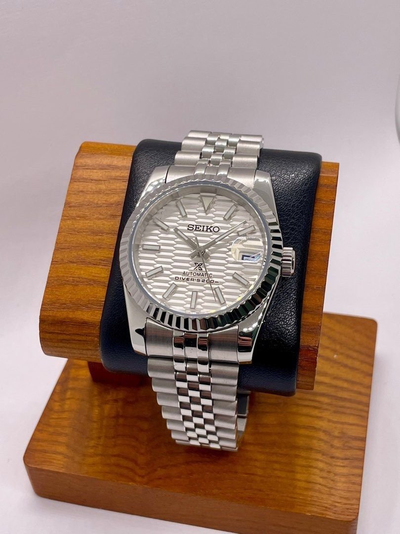 white textured dial Seiko NH35 mod watch with fluted bezel and jubilee bracelet, angled close-up on dark background