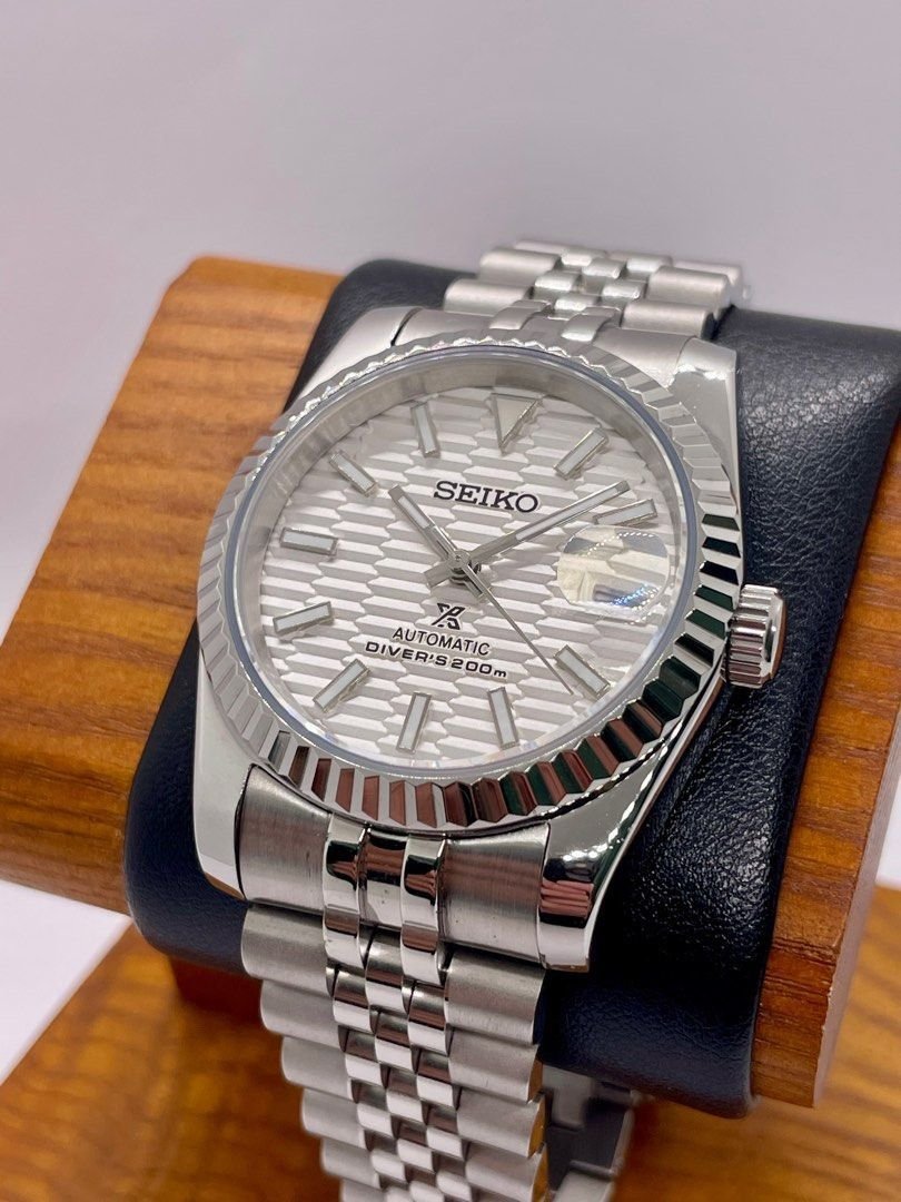 white textured dial Seiko NH35 mod watch with fluted bezel and jubilee bracelet, angled close-up on dark background