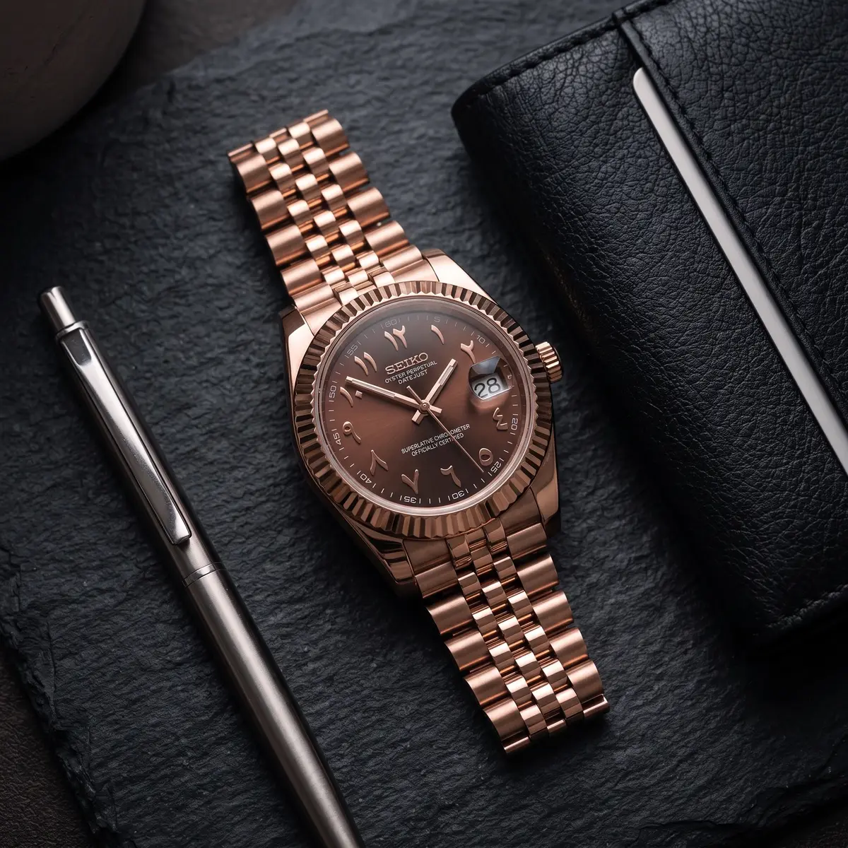 Seiko Mod Uhr DATE MOD | Roségold, braunes Zifferblatt mit arabischen Ziffern – Automatik – Flatlay auf Schiefer – MedoMods