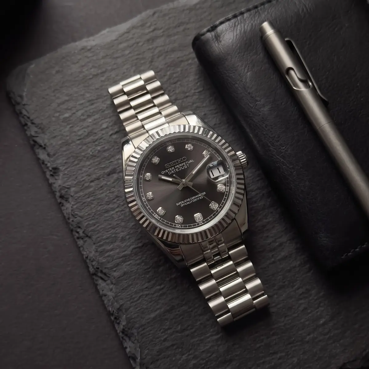 Seiko Mod Uhr DATE MOD | Stahl, schwarzes Zifferblatt – Automatik – Flatlay auf Schiefer – MedoMods