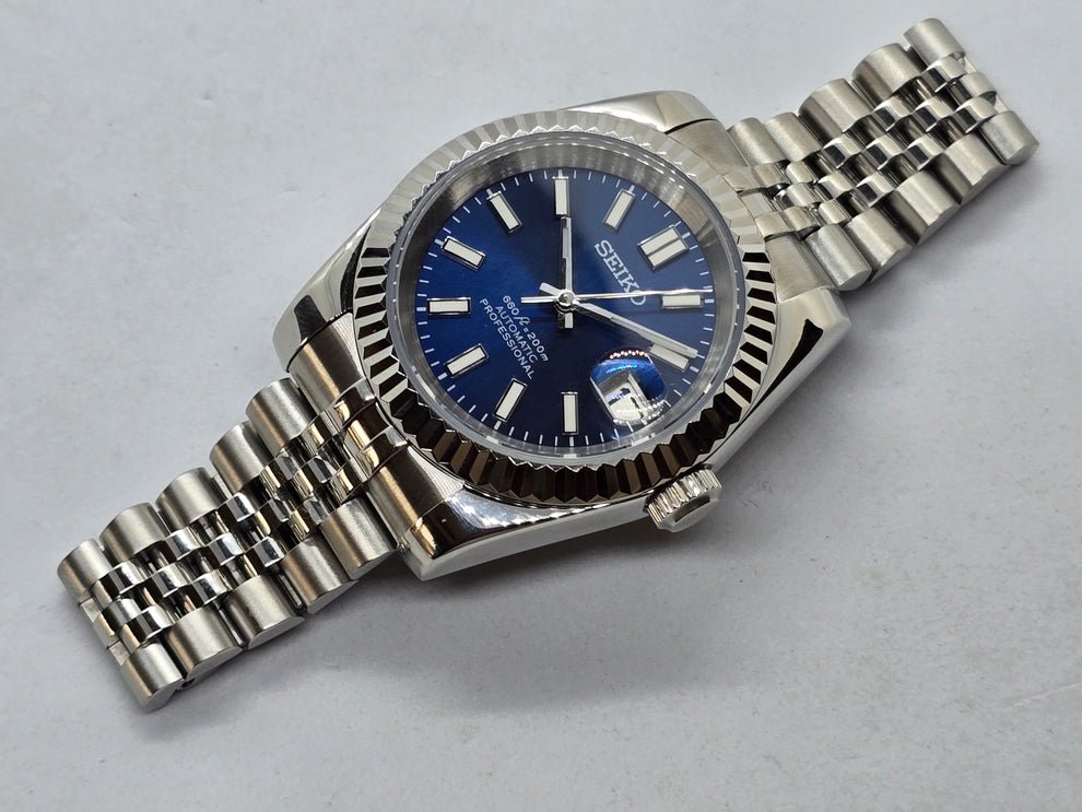 angled close-up of blue sunburst dial Seiko mod watch showing date window and fluted bezel