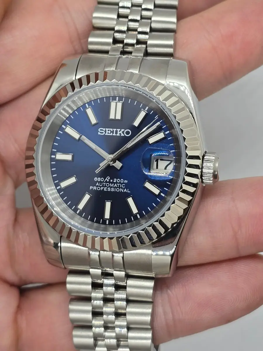 full shot of blue dial Datejust style Seiko mod watch on stainless steel jubilee bracelet, white background