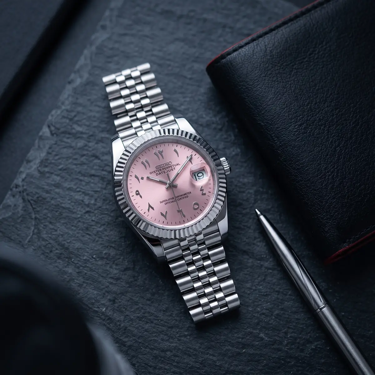 Seiko Mod Uhr DATE MOD | Stahl, rosa Zifferblatt mit arabischen Ziffern – Automatik – Flatlay auf Schiefer – MedoMods