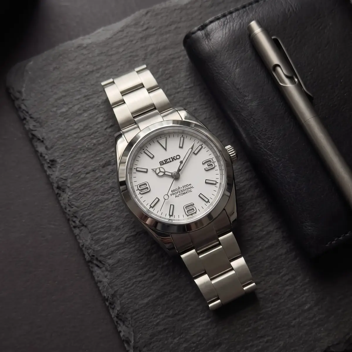 Seiko Mod Uhr DATE MOD | Stahl, weißes Zifferblatt – Automatik – Flatlay auf Schiefer – MedoMods