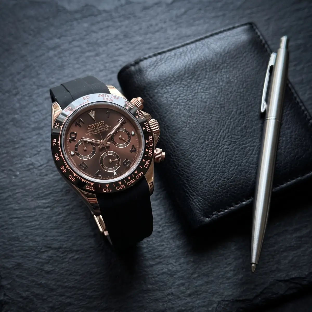 Seiko Mod Uhr TONA MOD | Schwarzes Kautschukarmband mit schwarzen und roségoldenen Ziffern – 40 mm – Flatlay auf Schiefer – MedoMods